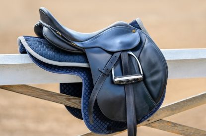 Black Saddle Hanging on Fence