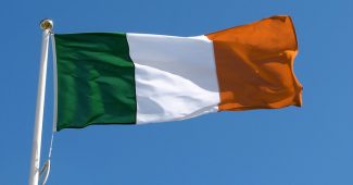 Irish Flag on Pole Against Clear Blue Sky
