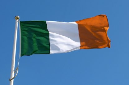 Irish Flag on Pole Against Clear Blue Sky