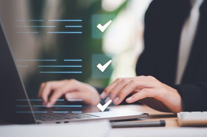 Businessperson Completing Checks on Laptop