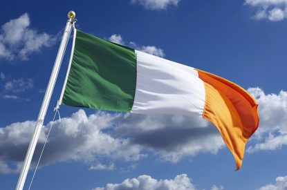 Irish Flag Waving Against Blue Cloudy Sky