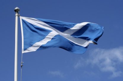 Flag of Scotland on Pole Against Blue Sky