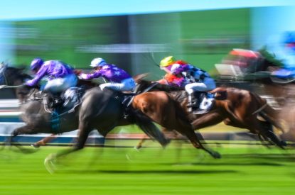 Blurred Horses Racing Past Big Screen
