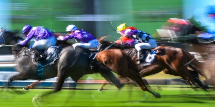 Blurred Horses Racing Past Big Screen