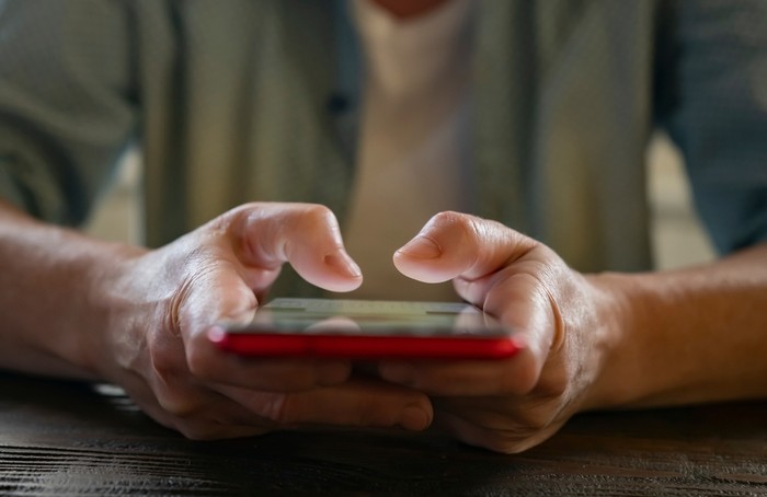 Hands of Man Using Red Smartphone