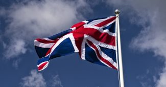 UK Flag on Pole Against Blue Cloudy Sky
