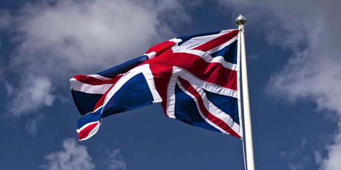 UK Flag on Pole Against Blue Cloudy Sky