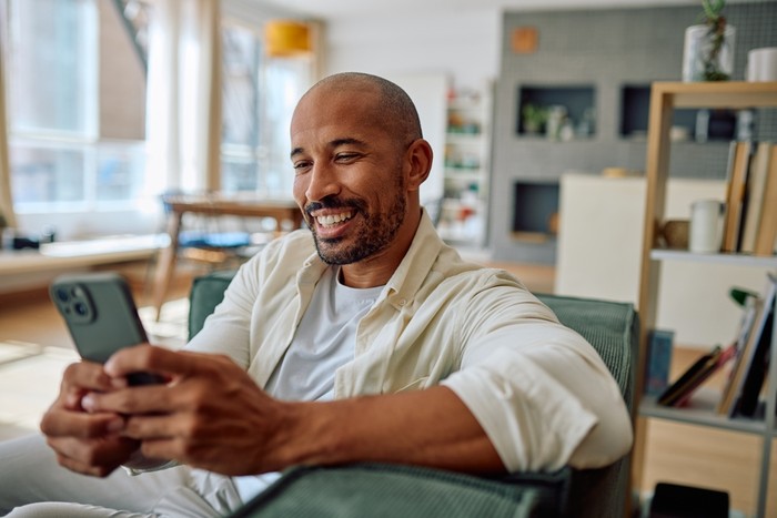 Smiling Man on Sofa with Phone