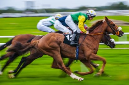 Three Horses Racing Against Rail