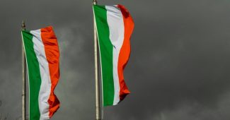 Two Ireland Flags Against Dark Grey Skies