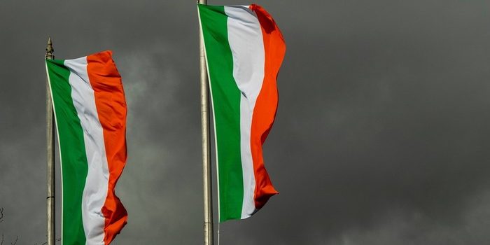 Two Ireland Flags Against Dark Grey Skies