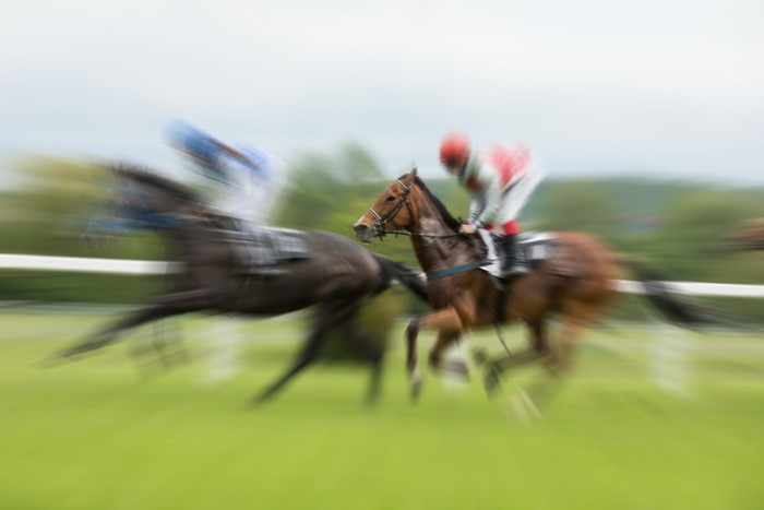 Two Motion Blurred Racehorses Against Rail